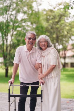 Mutlu Asyalı yaşlı çift aktif emeklilik yaşam tarzının keyfini çıkararak parkta yürür.