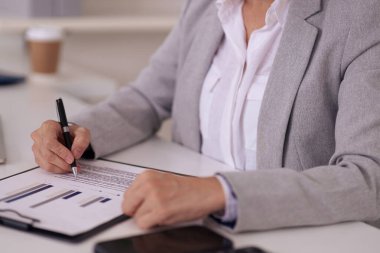 Yetişkin iş dünyası uzmanları finansal verileri titizlikle gözden geçirir ve modern ofis ortamındaki bir rapor üzerine notlar yazarlar. Detaylara odaklanırlar.