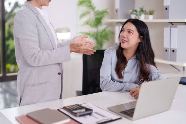 Asyalı kadın profesyoneller modern ofiste tartışırlar. Yaşlı kadın genç meslektaşına rehberlik eder. Kariyer geliştirme danışmanlığı işbirliği üzerine odaklanın.