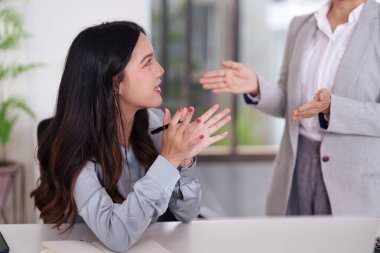 Ofiste iki Asyalı profesyonel kadın aktif olarak iş stratejilerini tartışıyor. Çözümler ve gelecek planları üzerinde işbirliği yapıyorlar..