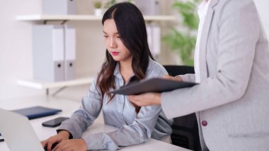 Genç iş adamları, modern teknolojiyi parlak bir iş ortamında kullanarak projede işbirliği yapıyorlar.