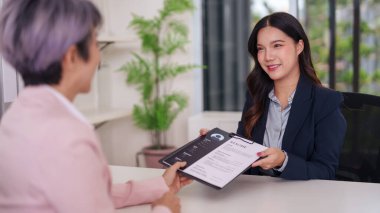 Kendine güvenen Asyalı kadın başvuru sahibi modern bir ofiste mülakata devam ediyor. Resim, kariyer arayışının önemli ilk adımını yakalar.