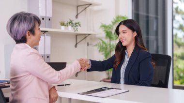İki farklı Asyalı kadın, parlak bir profesyonel çalışma alanında el sıkışarak iş sözleşmesi imzalıyorlar. Kariyer başarısı için yeni girişimciler işe alıyorlar.