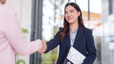 Asyalı iş arayan, bir mülakatçıyla güven içinde tokalaşıyor. Bu profesyonel toplantı yeni bir kariyerin başlangıcını simgeliyor..