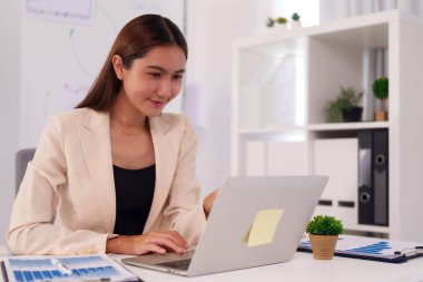 Yetişkin Asyalı iş adamları modern bir ofiste işbirliği yapıyorlar. Önemli finansal verileri gözden geçiriyorlar ve şirketlerinin gelecekteki büyümesi için stratejik planlar geliştiriyorlar.