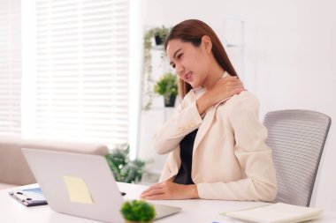 Asyalı profesyonel kadın boyun omuz rahatsızlığı çekiyor. Ofisteki uzun süreli bilgisayar kullanımından kaynaklanan yorgunluk stresi. İş yeri sağlık sorunları.