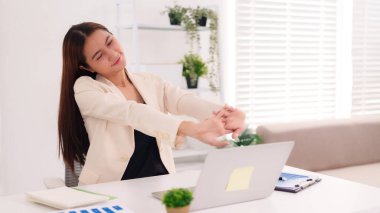 Asyalı yetişkin kadın, iş sırasında rahatlamak için esniyor. Rahatlığı teşvik ediyor. Modern ofis çevresi iş uzak çalışma konsepti.