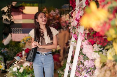 Genç Asyalı kadın gülümsüyor güzel çiçekçiye bakıyor canlı çiçekçi müşteri mutlu yetişkin kadın renkli çiçekçiyi seçiyor