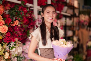 Gülümseyen Asyalı kadın bahar özel günleri için harika bir çiçekçide güzel bir çiçek buketi tutuyor.