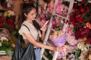 Gülümseyen bayan müşteri büyüleyici bir perakende mağazasında güzel çiçekler ve modern çiçek aranjmanlarını keşfediyor. Renkli çiçekli atmosferin tadını çıkarıyorum..