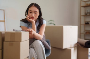 Yetişkin Asyalı kadın üzgün görünüyor. Stresli ev taşıma sırasında etrafını bir sürü kutuyla sarmışlar.