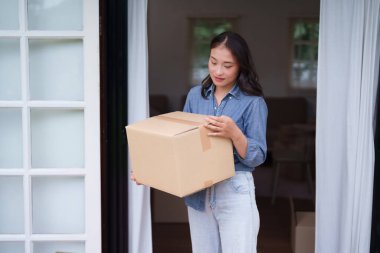 Asyalı kadın kahverengi kutuyu kapı eşiğinde tutuyor. Ev taşınmasına ya da paket almaya hazırlanıyor. Yeni bölüm kişisel yolculuğunu temsil ediyor.