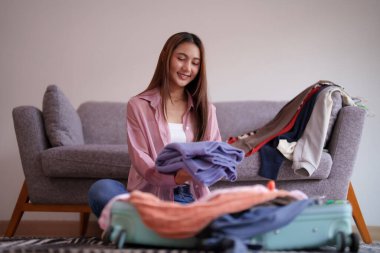 Yetişkin Asyalı kadın seyahat kıyafetlerini paketliyor. Heyecan verici tatil yolculuğuna hazırlanıyor.