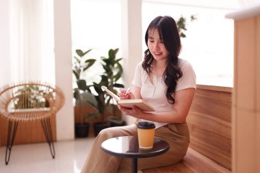 Asyalı kadın gelecekteki projeler için notlar yazıyor. Huzurlu çevre dijital göçebe yaşam tarzı.