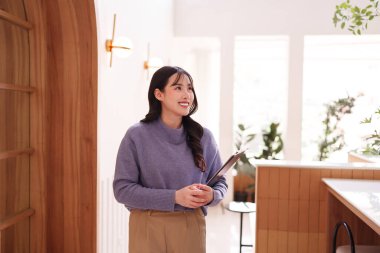 Neşeli Asyalı kadın, parlak, modern bir kafe profesyonel kadın yetişkin planlama projesinde iş işleri için panoyu hazır tutuyor.