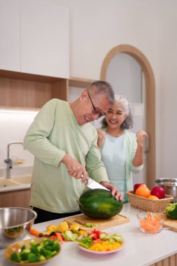 Neşeli, yaşlı yetişkinler birlikte yemek pişirmekten zevk alıyorlar ve sağlıklı ve hayat dolu taze sebzelerle sağlıklı yemekler yapıyorlar..