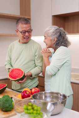 Asyalı son sınıf çifti birlikte sağlıklı yemekler hazırlarken mutlu bir yaşam tarzı ev yapımı taze sebzeler sağlıklı..