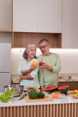 Yaşlı Asyalı çift temiz bir mutfakta taze meyve sebzeleri hazırlıyor. Sağlık mutluluğuna odaklanmış sağlıklı yemek yapma tarzını seviyorlar..