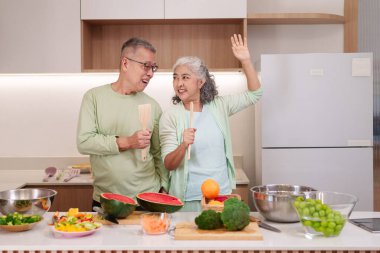 Gülümseyen Asyalı yaşlı kadın birlikte yemek pişiriyor besleyici yemekler pişiriyor taze sebzeler, meyveler, modern, neşeli ev ortamları.