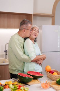 Sevgi dolu Asyalı yaşlı çift mutfaklarını paylaşıyor taze sebzeler hazırlıyor sağlıklı meyveler, ev yaşamının neşesini kucaklıyor