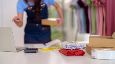 Entrepreneur prepares fashion garments for shipment. Efficient logistics for small business. Packaging online purchases for delivery.