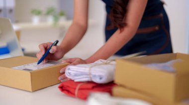 Dedicated adult female prepares parcels for dispatch managing her successful ecommerce venture from a comfortable workspace ensuring prompt delivery worldwide