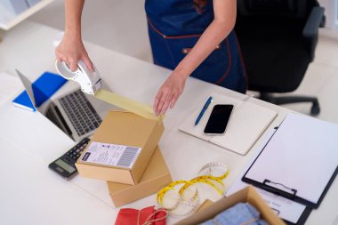 Entrepreneur efficiently packs merchandise managing her online shop processing orders for swift customer delivery from a cozy home setup