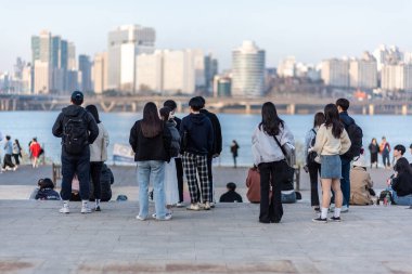 30 Mart 2023 'te Güney Kore, Seul' deki Han nehri üzerindeki Yeouido Parkı 'nda piknik yapan insanlar