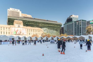 İnsanlar 23 Aralık 2023 'te Güney Kore' deki Belediye Binası 'nın önündeki geçici buz pateni pistinde buz pateni yapıyorlar.