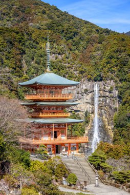 Three story pagoda of Seiganto-ji Tendai Buddhist temple in Wakayama Prefecture, Japan with Nachi Falls in the background clipart