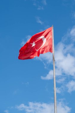 Gökyüzüne karşı rüzgarda dalgalanan bayrak direğinde Türkiye Cumhuriyeti bayrağı
