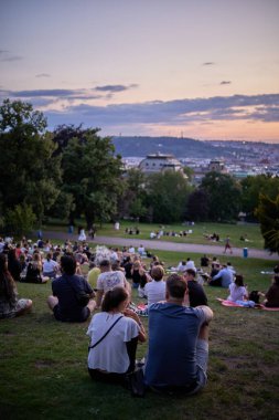 Young people picnic and enjoy sunset view of Prague cityscape in summer in Riegrovy Sady park in the Vinohrady district in Prague, capital of Czech Republic on 22 July 2024 clipart