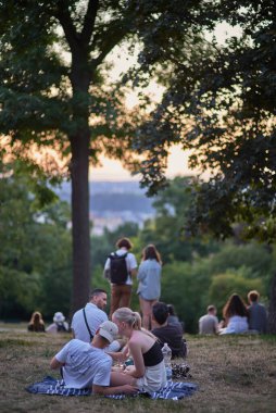 Young people picnic and enjoy sunset view of Prague cityscape in summer in Riegrovy Sady park in the Vinohrady district in Prague, capital of Czech Republic on 22 July 2024 clipart