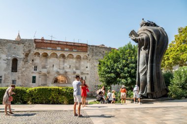 Hırvatistan 'ın Split kentindeki Giardin Parkı' nda 29 Ağustos 2024 'te, Ortaçağ Hırvat Katolik Başpiskoposu İvan Mestroviç' in eseri olan Piskopos Grgur Ninski (Nin Heykeli) önündeki turistler görülüyor.