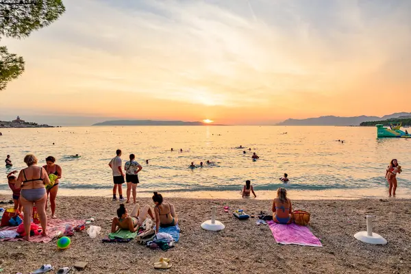 24 Ağustos 2024 'te Hırvatistan' ın Adriyatik Denizi, Dalmaçya bölgesindeki Makarska Riviera plajında gün batımını izleyen insanlar