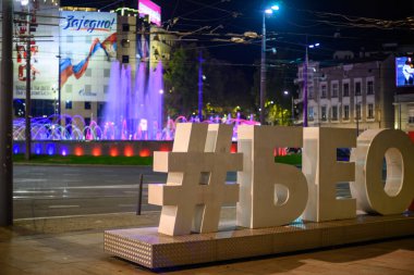 30 Eylül 2024 'te Sırbistan' ın başkenti Belgrad 'daki Slavija Meydanı kavşağındaki aydınlık çeşme ve Belgrad' daki turist hashtag 'ının gece manzarası