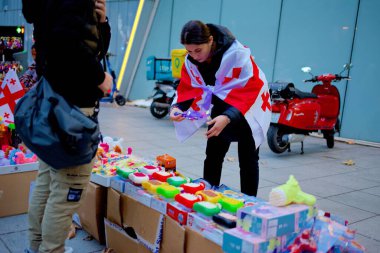 20 Ekim 2024 'te Gürcistan' ın başkenti Tiflis 'teki Avrupa Birliği entegrasyon ve üyeliğini destekleyen gösteriler için Mart ayı öncesinde bayraklar satan sokak satıcısı