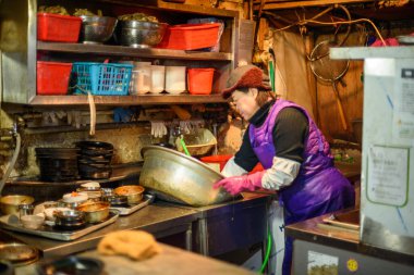 Woman preparing food for a street food stall in Myeongdong shopping district in downtown Seoul, capital of South Korea on 27 January 2024 clipart