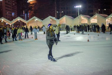 İnsanlar 9 Şubat 2024 'te Güney Kore' nin Seul kentindeki belediye binasının önündeki geçici buz pateni pistinde gece yarısı buz pateni yapıyorlar.