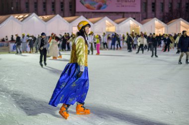 İnsanlar 9 Şubat 2024 'te Güney Kore' nin Seul kentindeki belediye binasının önündeki geçici buz pateni pistinde gece yarısı buz pateni yapıyorlar.