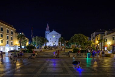 Hırvatistan 'ın Adriyatik kıyı şeridinde 22 Ağustos 2024' te popüler turizm tatil beldesi Makarska 'daki Eski kasaba meydanının gece manzarası