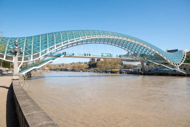 1 Nisan 2025 'te Gürcistan' ın başkenti Tiflis 'teki Kura Mtkvari nehri üzerinde barış köprüsü, çelik ve cam bina yaya köprüsü