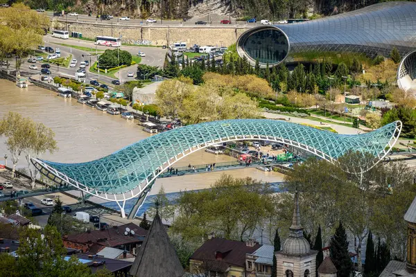 4 Nisan 2025 'te Gürcistan' ın başkenti Tiflis 'teki Kura Mtkvari nehri üzerindeki Barış Köprüsü, çelik ve cam inşaat yaya köprüsünün hava manzarası