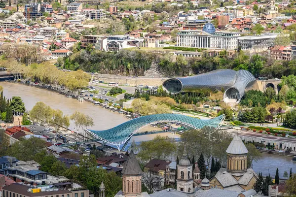 4 Nisan 2025 'te Gürcistan' ın başkenti Tiflis 'teki Kura Mtkvari nehri üzerindeki Barış Köprüsü, çelik ve cam inşaat yaya köprüsünün hava manzarası