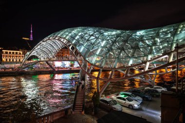 24 Nisan 2025 'te Gürcistan' ın başkenti Tiflis 'te, Kura Mtkvari nehri üzerindeki barış köprüsü, çelik ve cam bina yaya köprüsü gece aydınlandı.