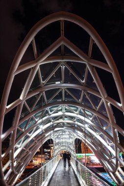 24 Nisan 2025 'te Gürcistan' ın başkenti Tiflis 'te, Kura Mtkvari nehri üzerindeki barış köprüsü, çelik ve cam bina yaya köprüsü gece aydınlandı.