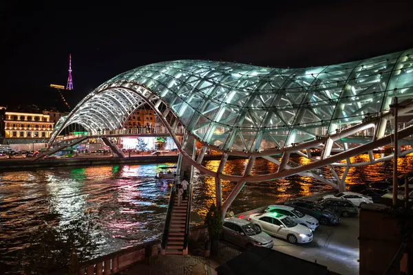 24 Nisan 2025 'te Gürcistan' ın başkenti Tiflis 'te, Kura Mtkvari nehri üzerindeki barış köprüsü, çelik ve cam bina yaya köprüsü gece aydınlandı.