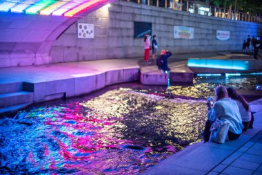 10 Ekim 2021 'de Güney Kore' nin başkenti Seul 'deki halk parkında Cheonggyecheon Stream' de dinlenen insanlar