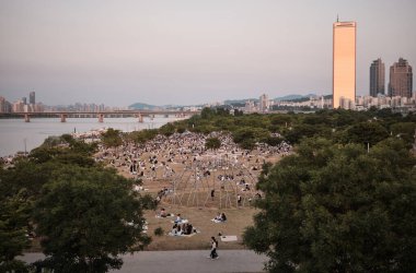 28 Mayıs 2022 'de Güney Kore' nin başkenti Seul 'de Han Nehri' ndeki Yeouido Parkı 'nda piknik yapan insanlar görülüyor.