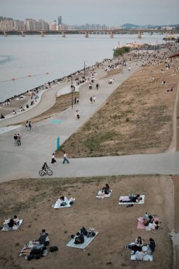28 Mayıs 2022 'de Güney Kore' nin başkenti Seul 'de Han Nehri' ndeki Yeouido Parkı 'nda piknik yapan insanlar görülüyor.